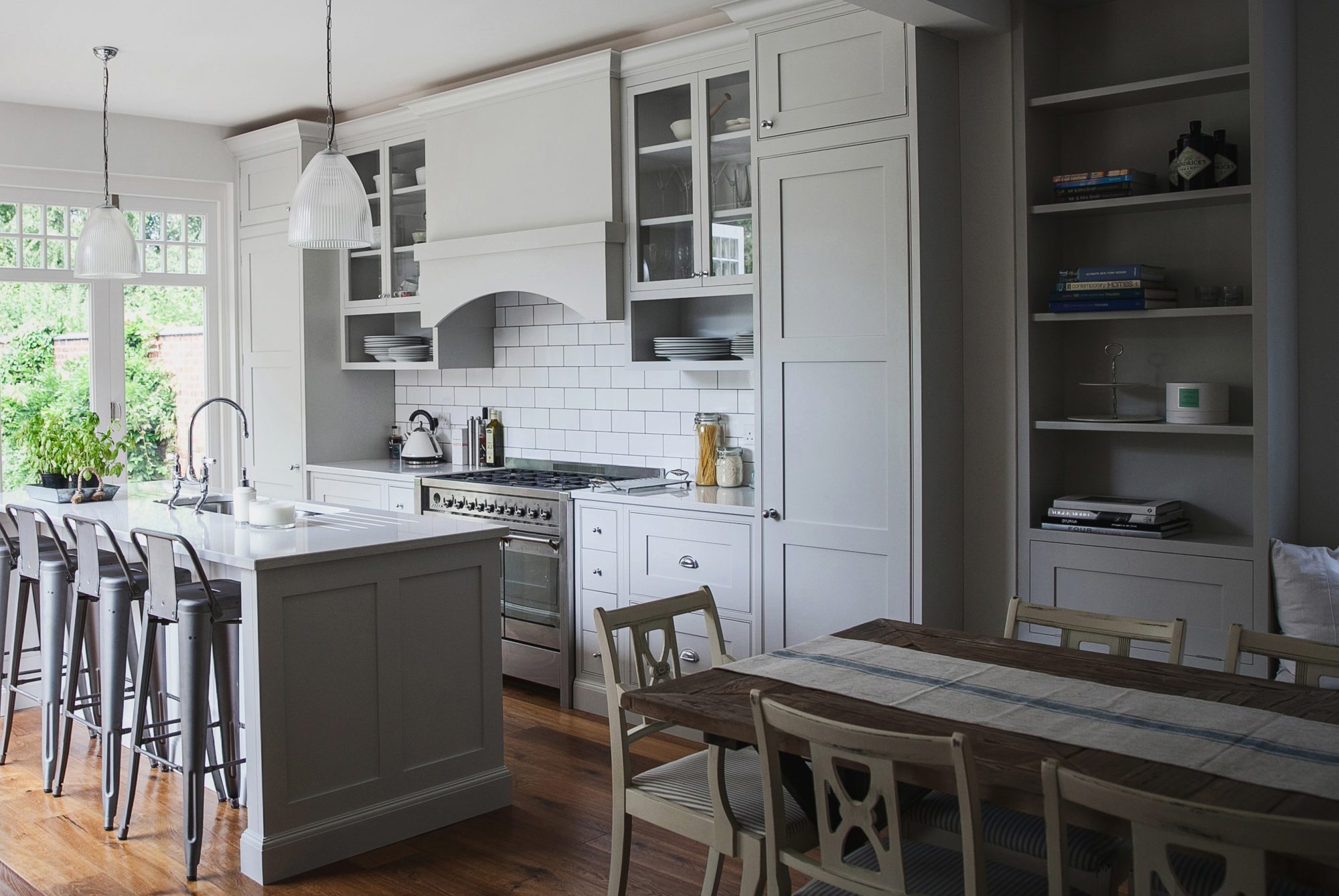 Bespoke kitchen in lichfield Staffordshire , with tall cupboard at each end , range cooker in the middle and island with seating facing the range cooker.